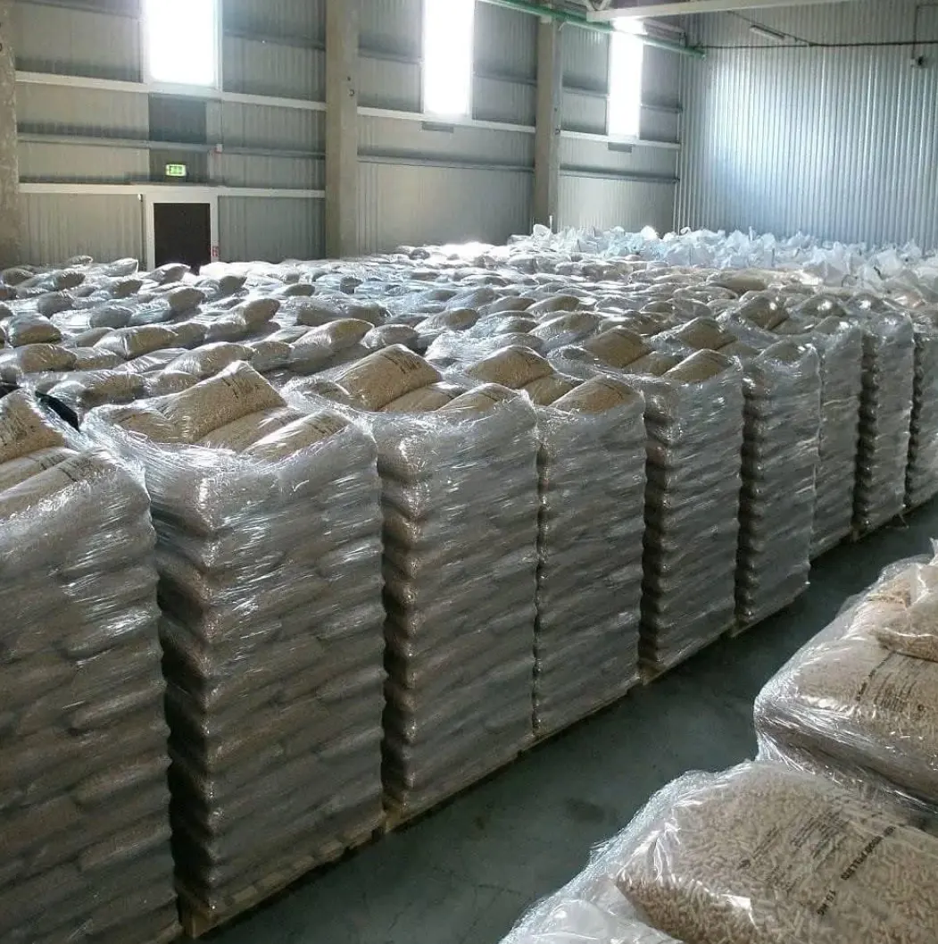 Acacia wood pellet bags stacked on pallets in a warehouse