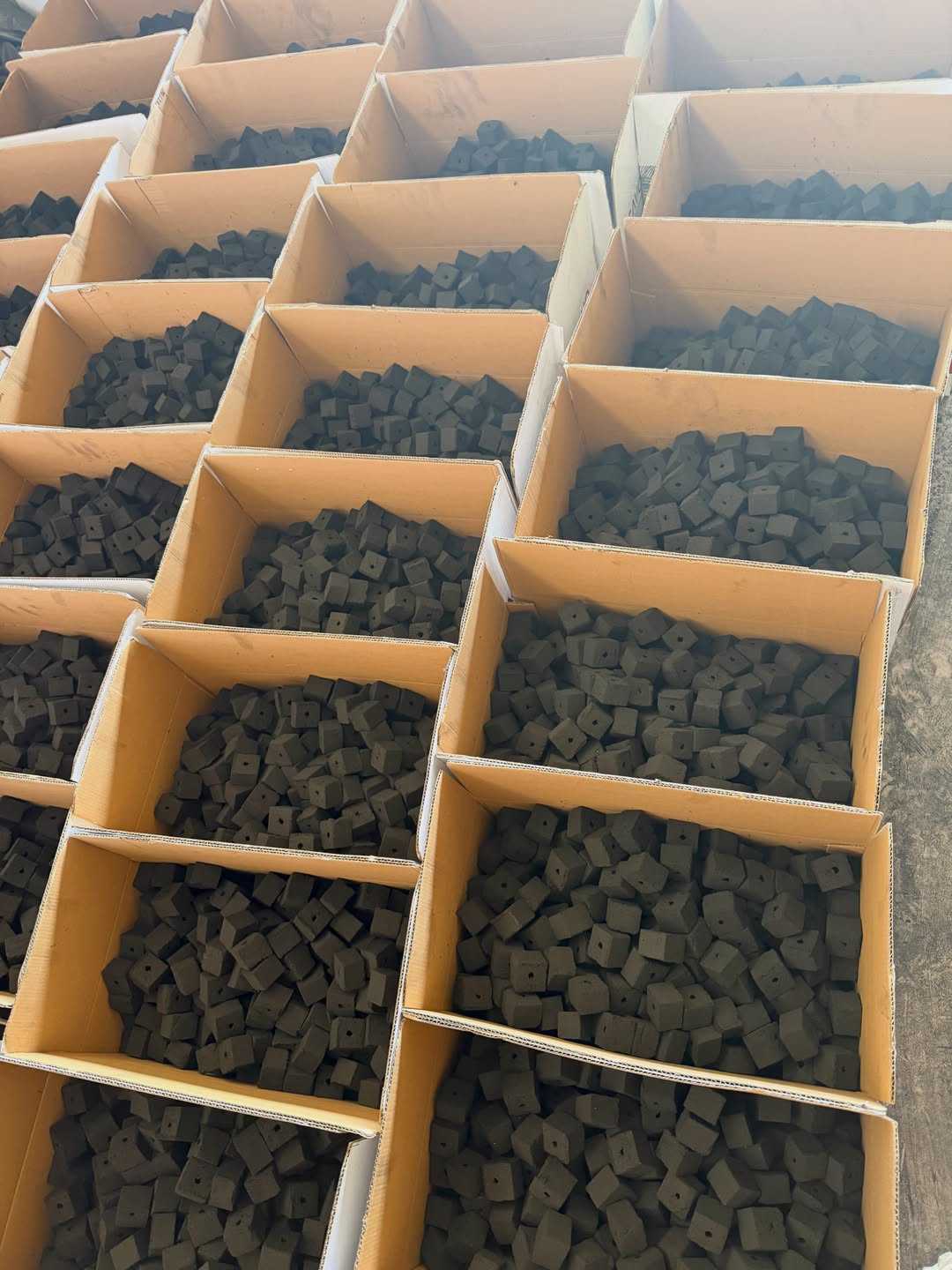 Boxes of cube-shaped shisha charcoal stacked in a warehouse